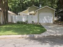Light green house with white fence, garage, and well-manicured lawn at 513 Harvard Pl, Apopka, FL 32703