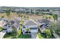 Aerial view of a two-story house with a large backyard and pool in a quiet residential neighborhood at 323 Plumoso Loop, Davenport, FL 33897