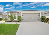 Charming home featuring a two-car garage and well-maintained front lawn under a bright, cloudy sky at 4505 Hummingbird Ln, Haines City, FL 33844