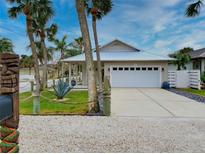 A beach-style home with a white garage door, palm trees, and a gravel driveway at 821 E 1St Ave, New Smyrna Beach, FL 32169