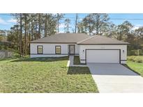 White house with gray roof, two-car garage, and a well-manicured lawn at 1608 Airmont Ave, Deltona, FL 32725