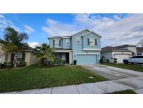 Two-story light blue house with a two-car garage and landscaped lawn at 1706 Chatsworth Cir, Saint Cloud, FL 34771