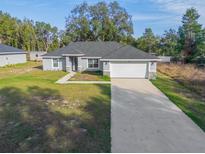 Newly built home with gray exterior, white garage door, and landscaped yard at 1780 Sw 168Th Loop, Ocala, FL 34473