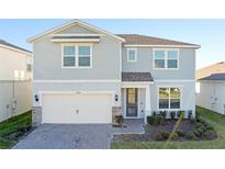 Two-story home with gray siding, white garage door, and landscaping at 1914 Summer Serenity Dr, Kissimmee, FL 34744