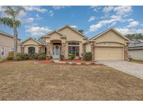 One-story house with a tan exterior, brick accents, and a two-car garage at 216 Blue Crystal Dr, Deland, FL 32720