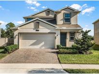 Two-story house with beige exterior, two-car garage, and landscaping at 2928 Muller Oak Loop, Ocoee, FL 34761