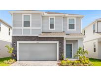 Two-story house with gray siding, stone accents, and a two-car garage at 3937 Lana Ave, Davenport, FL 33897