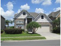 Two-story home with a stone veneer, tan stucco, a two-car garage, and attractive landscaping at 1108 Darnaby Way, Orlando, FL 32824