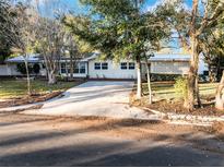 White mid-century modern home with large windows, mature trees, and a long driveway at 1642 Athens St, Lakeland, FL 33803