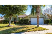 Green house exterior with a two-car garage and manicured lawn at 5649 Magnolia Bloom Ter, Oviedo, FL 32765