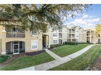 Exterior of the apartment building showcasing landscaping and a walkway at 2303 Butterfly Palm Way # 201, Kissimmee, FL 34747