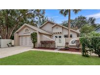 Tan house with attached garage and landscaped yard at 600 Torrey Oaks Ct, Longwood, FL 32750