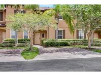 Tan two-story townhome with a landscaped front yard and brick paver driveway at 120 Palermo St, Davenport, FL 33897