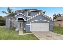 Two-story house with gray exterior, white garage door, and green lawn at 2556 Volta Cir, Kissimmee, FL 34746