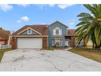 Two-story house with attached garage, landscaping, and a palm tree at 5451 Red Bone Ln, Orlando, FL 32810