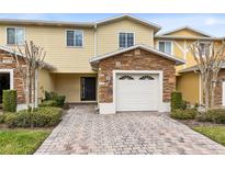Inviting two-story townhome boasts a charming exterior, featuring stone accents and a paved driveway at 10125 Shadow Leaf Ct, Orlando, FL 32825