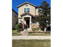 Tan two-story house with dark brown door, landscaping, and walkway at 11555 Charnock Dr, Windermere, FL 34786