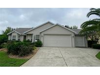 Tan house with double garage and manicured landscaping at 2530 Saffron Ln, The Villages, FL 32162