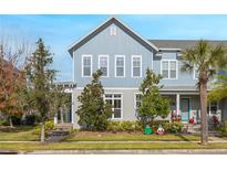 Two-story house with light blue siding, landscaping, and a front porch at 8763 Laureate Blvd, Orlando, FL 32827