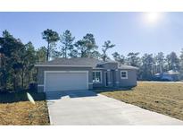 Newly constructed home with gray exterior, white garage door, and a driveway at 13375 Sw 63Rd Ave, Ocala, FL 34473