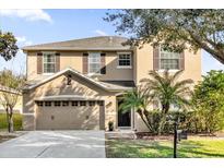 Two-story house with tan siding, brown accents, and a two-car garage at 20811 Sullivan Ranch Blvd, Mount Dora, FL 32757