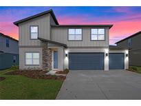 Two-story home with gray siding, stone accents, and a two-car garage at 2330 Gold Dust Dr, Minneola, FL 34715