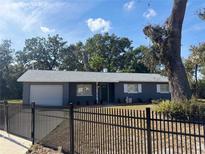Cute ranch home with gray exterior, fenced yard, and mature trees at 5460 Hondo Way, Orlando, FL 32810