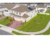Two-story home featuring a brick driveway, two-car garage, manicured lawn, and solar panels at 14352 Noto Ave, Clermont, FL 34714
