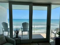 Living area with ocean view from sliding doors and balcony with chairs at 5203 S Atlantic Ave # 815B, New Smyrna Beach, FL 32169