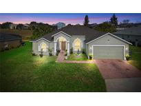 Attractive one-story house with a landscaped lawn and brick driveway at 645 Dolcetto Dr, Davenport, FL 33897