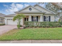 Beautiful one-story home with a landscaped lawn, brick driveway, and a charming front porch at 13607 Zori Ln, Windermere, FL 34786