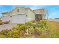 Landscaped yard, two-car garage, and light-green exterior at 1987 Key Bay Trl, Kissimmee, FL 34747