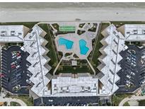 Overhead shot of condominium complex with a swimming pool, tennis court, and ample parking at 2401 S Atlantic Ave # C306, New Smyrna Beach, FL 32169