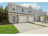 Gray two-story townhome with brick paver driveway and an attached one-car garage at 3332 Thicket St, Tavares, FL 32778