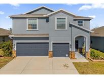 Two-story house with gray siding, two-car garage, and landscaped yard at 4538 Cortland Dr, Davenport, FL 33837