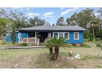 Charming blue house with a white porch and landscaped yard at 23627 Franklin Ave, Sorrento, FL 32776