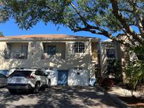 Multi-level condo with attached garages and balconies, shaded by a mature tree on a sunny day at 7240 Westpointe Blvd # 1115, Orlando, FL 32835