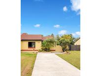 Cute yellow house with red tile roof, landscaped yard, and concrete driveway at 743 Golden Sunshine Cir, Orlando, FL 32807