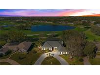 Stunning aerial view of a home with a circular driveway overlooking a serene lake and lush green golf course at 8513 Bay Hill Blvd, Orlando, FL 32819