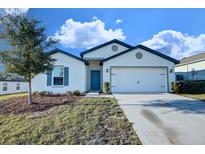 Charming single-story home featuring a well-manicured lawn and a bright blue front door at 1147 Moyle Way, Mascotte, FL 34753