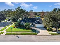 Aerial view of single-story house with a two-car garage, landscaped yard, and pond in the background at 2073 Shadyhill Ter, Winter Park, FL 32792