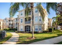 Tan building exterior with palm trees and landscaped grounds at 2300 Butterfly Palm Way # 205, Kissimmee, FL 34747