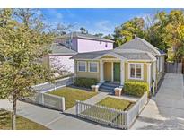 Charming yellow bungalow with white picket fence, green door, and landscaped yard at 123 N Hyer Ave, Orlando, FL 32801