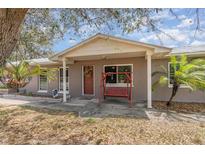 Ranch-style home with covered porch, mature trees, and a swing at 1432 Libby Rd, Babson Park, FL 33827