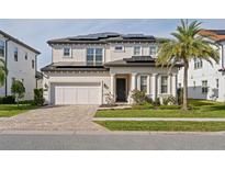 Two-story house with solar panels, a three-car garage, and a manicured lawn at 10631 Royal Cypress Way, Orlando, FL 32836