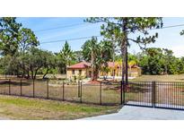 Single-story home with red tile roof and gated entrance at 13305 Lacebark Pine Rd, Orlando, FL 32832