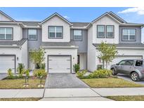 Two-story townhome with gray and white siding, two-car garage, and landscaped front yard at 1479 Brookdale Ct, Oviedo, FL 32765