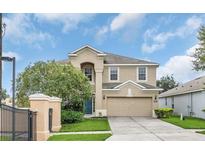 Two-story house with a beige exterior, two-car garage, and landscaping at 2715 Manesty Ln, Kissimmee, FL 34747