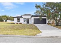 White house with black trim, a two-car garage, and a well-manicured lawn at 4670 Sw 142Nd Place Rd, Ocala, FL 34473