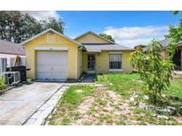 Cute yellow house with a single car garage and small front yard at 5633 Piney Ridge Dr, Orlando, FL 32808